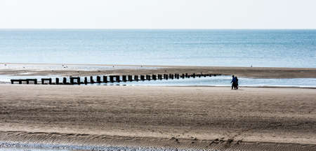 A couple take a leisurely stroll on Blackpool Beach, Lancashire, UK.の写真素材