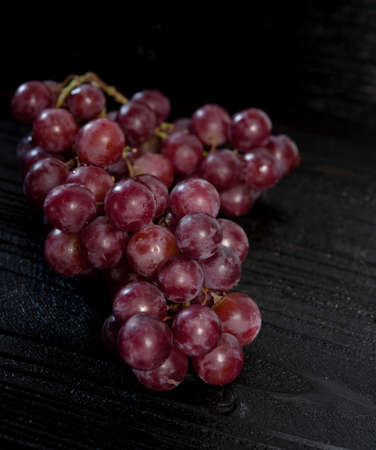 Bunch of red grape isolated on dark wood backgroundの写真素材