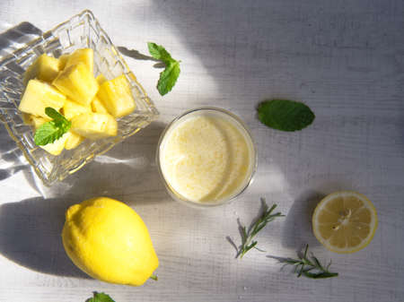 A glass of pineapple smoothie on wooden background with rays of the sun. Helthy food.