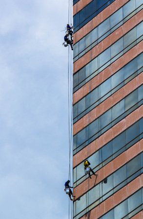 group of workers cleaning windows service on high rise buildingの写真素材