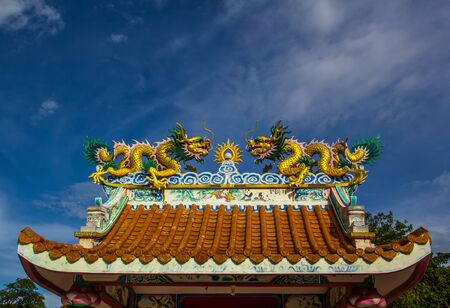 Chinese dragon statue on the roof with a sky blue backgroundの写真素材
