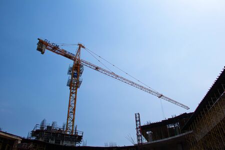 Yellow construction tower crane against blue skyの写真素材