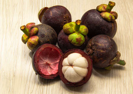 Mangosteen is the queen of fruits, with purple husk, placed on a wooden table.