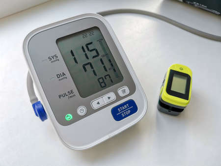Included tonometer monitor with normal blood pressure and pulse oximeter on a white surface