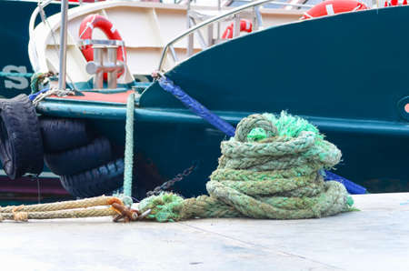 Rolled green nautical rope against of the moored yacht.