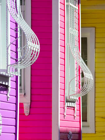 Fragment of a multicolor facade of the house with curved bars on the windows.