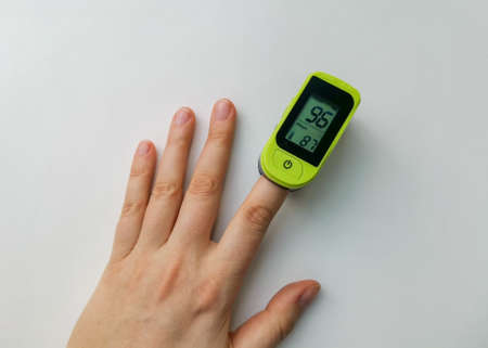Human hand with a pulse oximeter on the index finger on a white background