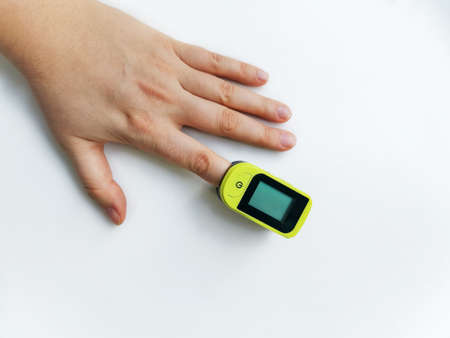 Human hand with a pulse oximeter on the index finger on a white background