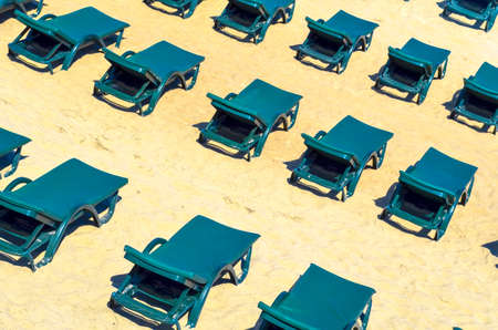 Rows of free green sun loungers on an empty sandy beachの写真素材