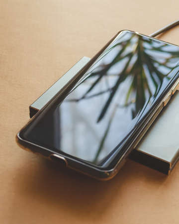 A phone is charging from a rectangular induction charger. Wireless charger