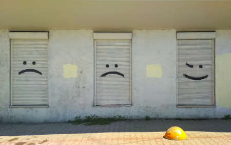 Three street windows of closed blinds with smiles painted on themの写真素材