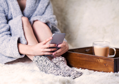 the girl is sitting with the phone in her hands. Breakfast in bedの写真素材