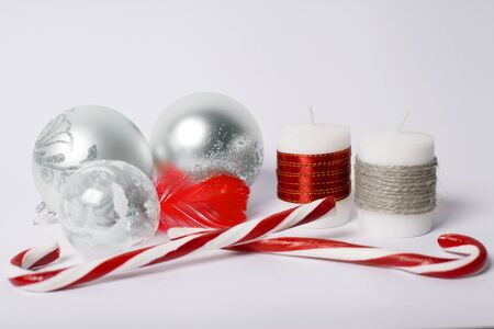 Christmas concept - silver christmas balls, candy-sticks and decorative candles on a white backgroundの写真素材