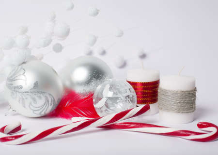 Christmas concept - silver christmas balls, candy-sticks and decorative candles on a white backgroundの写真素材