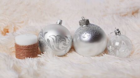 Christmas concept - silver christmas balls and decorative candle on a fur backgroundの写真素材