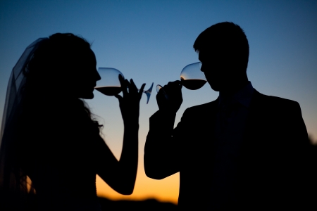 Bride and groom drink wine at sunset 