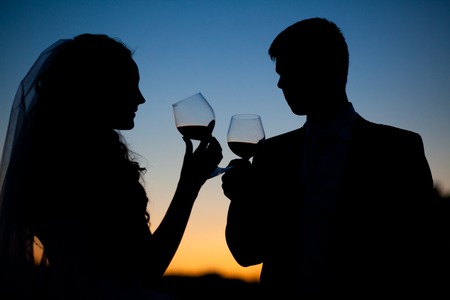 Bride and groom drinking wine at sunsetの写真素材