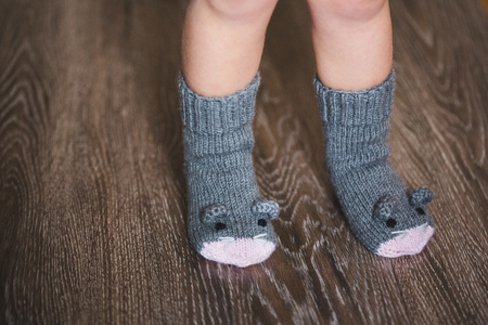 Baby feet in winter mouse socks on the wooden floorの写真素材