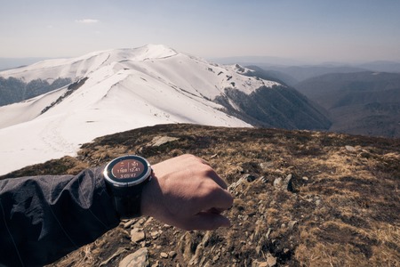 Runner checking progress on smart watch. Fit male runner exercise training and jumping outdoors in beautiful mountain nature landscapeの写真素材