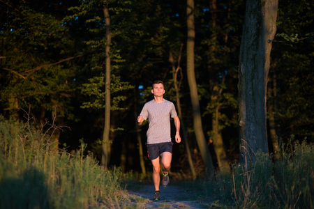 Sport running man in cross country trail run on sunsetの写真素材