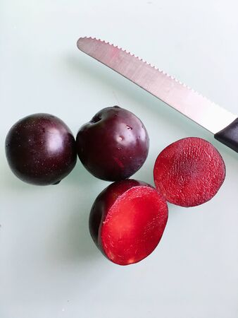 Half-cut pluot plum fruits on the table with knifeの写真素材