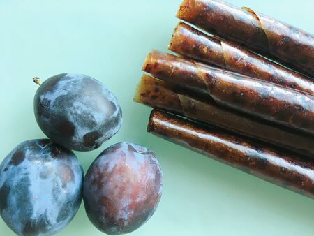 Sweet pureed fruit pastille. Fruit roll-ups homemade on a wooden background. Natural sweets from plum fruits.の写真素材