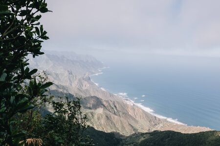 Aerial view of tropical beach and turquoise clear ocean water with small waves and palm trees forest in mountains. Tenerife, Spain. Travel tropical conceptの写真素材