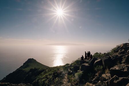 Young happy tourist on top of a mountain enjoying sea view before sunsetの写真素材