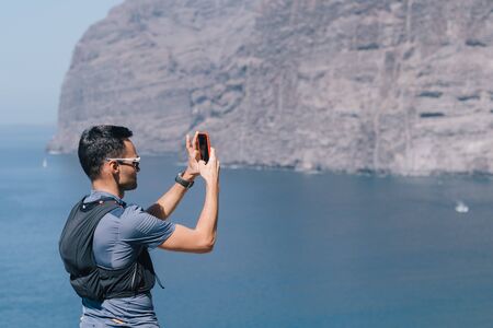 man tourist taking photos of sunset with mobile phone