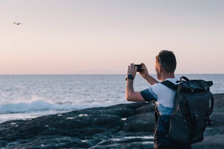 man taking photos of sunset with mobile phoneの写真素材