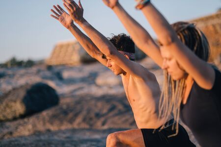 fitness, sport, and lifestyle concept - couple making yoga exercises on beachの写真素材
