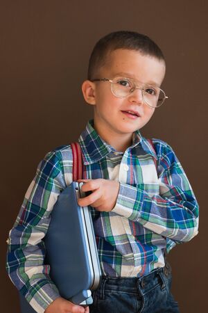 Portrait of a cute serious boy using a laptop. Child in glasses with a laptopの写真素材