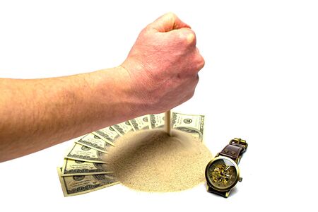 Hand pouring sand on dolars with a clock isolated on a white background