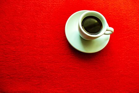 white cup with coffee on a red backgroundの写真素材