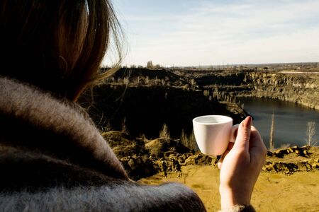 Woman with a cup of coffee on a canyon backgroundの写真素材