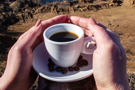 Female hands hug a cup of coffee on a canyon backgroundの写真素材