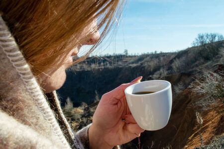 Woman holds morning coffee on sky and canyon backgroundの写真素材