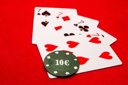 Four sevens and poker chip on a red backgroundの写真素材