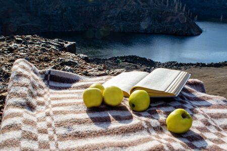 On a plaid are apples and a knoga against the backdrop of a canyonの写真素材