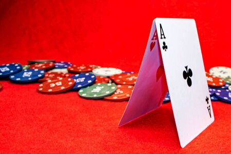 Two aces folded by a house on a red background