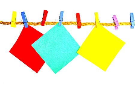 Multi-colored paper on multi-colored clothespins on a white backgroundの写真素材