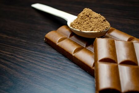 Porous chocolate, wooden spoon with cocoa on a black backgroundの写真素材