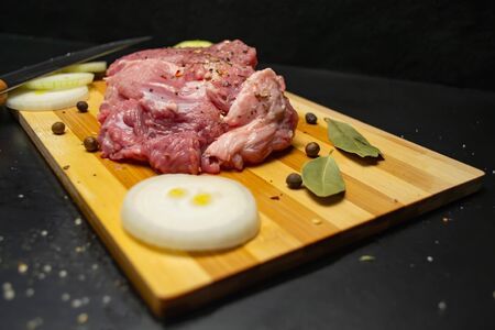 Fresh meat on a cutting board, onions and peppersの写真素材
