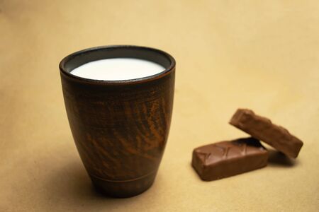 Milk in a brown clay cup, two chocolate barsの写真素材