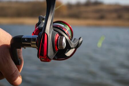 Fishing reel close-up on the background of the riverの写真素材
