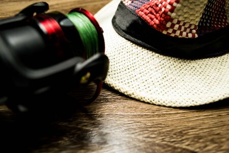 Hat, fishing reel on a wooden background.