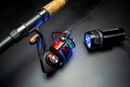 Fishing rod, flashlight on a black backgroundの写真素材