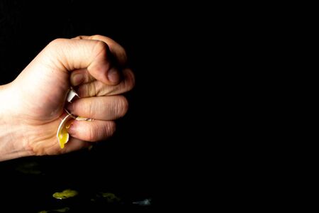 Male hand crushed a chicken egg, on a black backgroundの写真素材