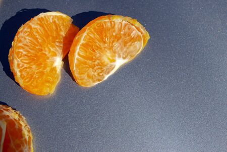 Pieces of orange mandarin on a gray backgroundの写真素材
