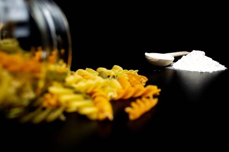 Pasta, spaghetti, flour, wooden spoon on a black backgroundの写真素材